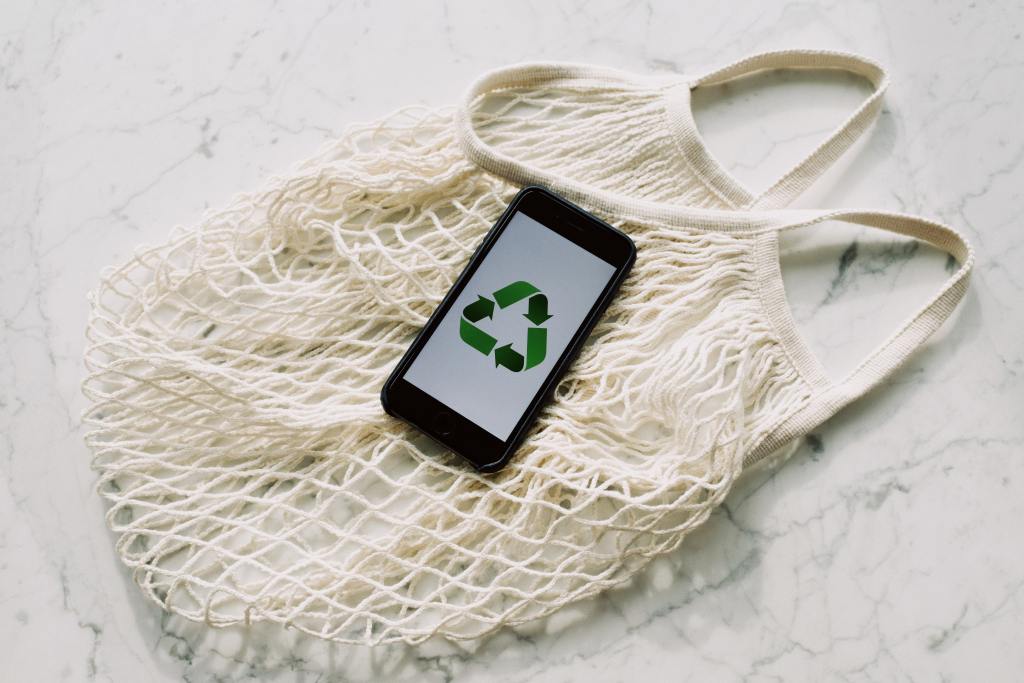 Uma sacola de papel e um celular com o símbolo da reciclagem.