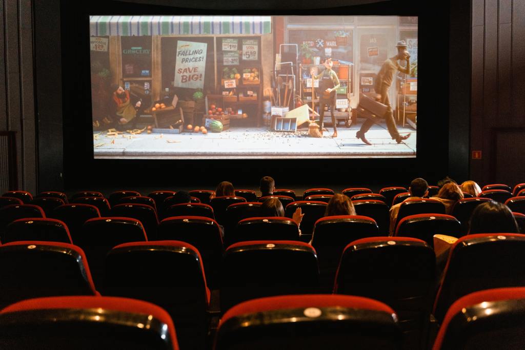 Sala de cinema com pessoas assistindo a um filme.
