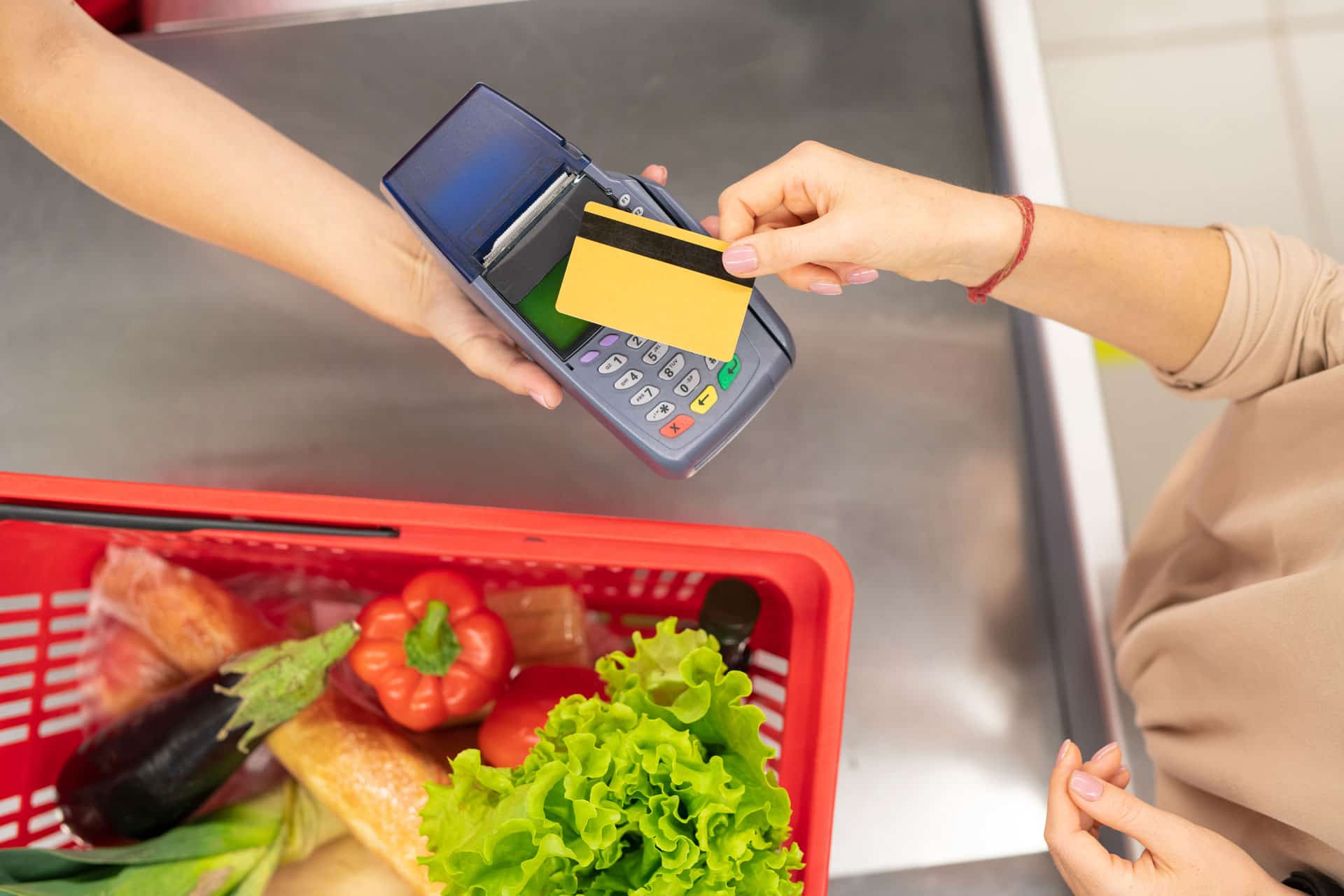 Mulher pagando suas comprar no supermercado com seu vale alimentação em uma maquina de cartão. 